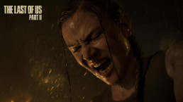 Plan serré en contre-plongée sur le visage d'Abby dans le jeu vidéo The Last of Us Part II. Il fait nuit, le personnage est visiblement en extérieur, comme l'indique la pluie qui tombe. Une lumière chaude l'éclaire légèrement, sans doute doute celle d'un feu. Le visage d'Abby est contracté, exprimant un effort ou une douleur.