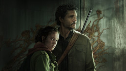 Portrait de Ellie et Joel, incarnés par Bella Ramsey et Pedro Pascal dans la série HBO. Ellie regarde vers la caméra tandis que Joel, juste derrière elle, regarde sur la droite. En arrière-plan nous voyons un mur gris recouvert par le cordyceps.