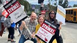Photo de Craig Mazin, Halley Gross et Merle Dandridge manifestant lors de la grève des scénaristes ainsi que des acteurs et actrices à Hollywood. Chacun porte une pancarte avec un slogan différent dessus.